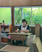 Woman sitting at a desk packaging up incense into bundles