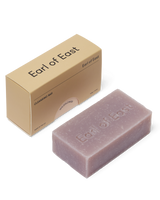 A soap bar next to its packaging box, with the Earl of East brand visible on both the bar and the box.