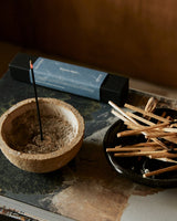 Close-up of lit Shinrin-Yoku incense stick creating aromatic smoke in a serene indoor environment