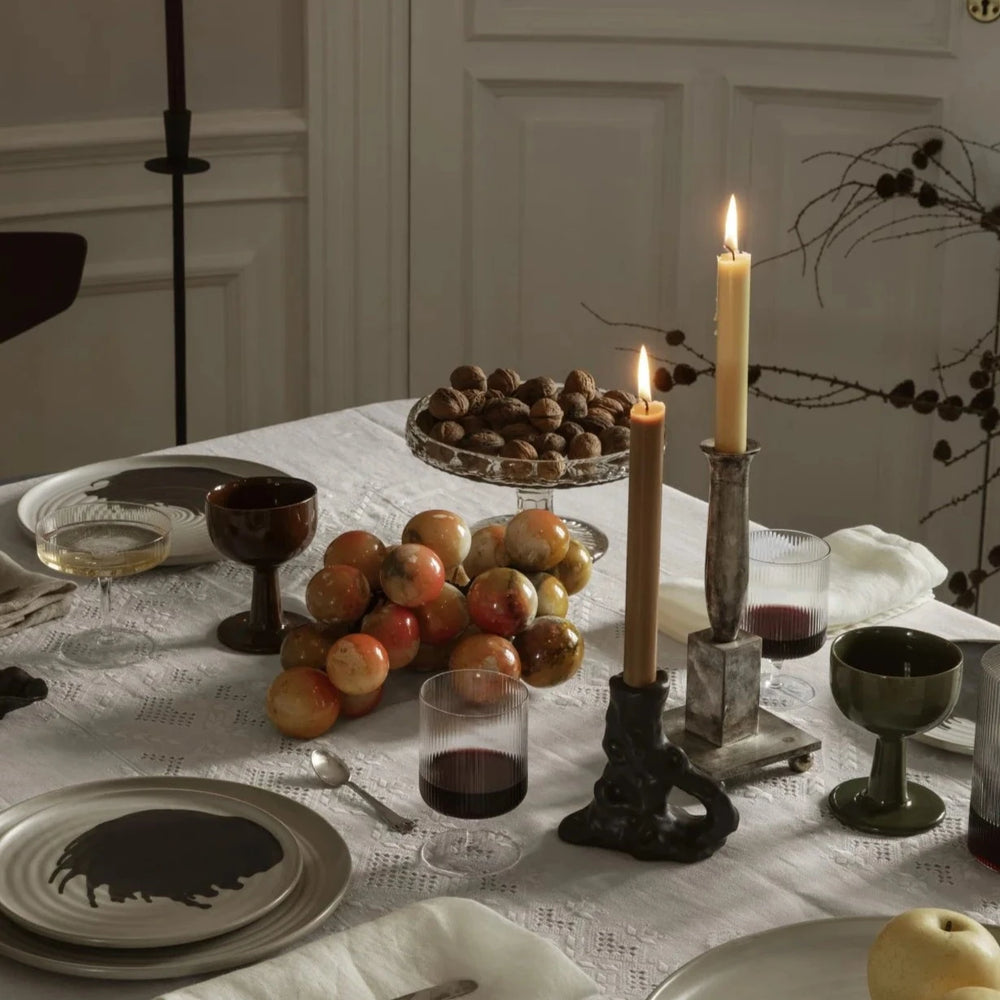 Single Dito Candle Holder, Dark Brown by ferm LIVING, holding a lit taper on a dinner table