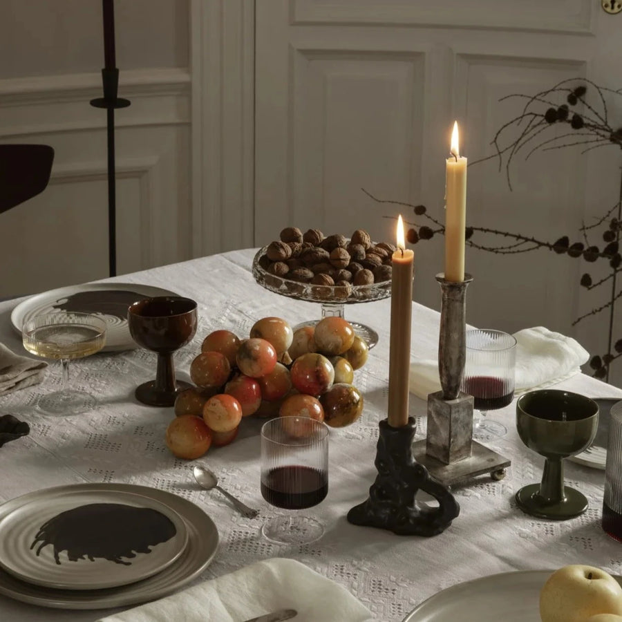 Single Dito Candle Holder, Dark Brown by ferm LIVING, holding a lit taper on a dinner table