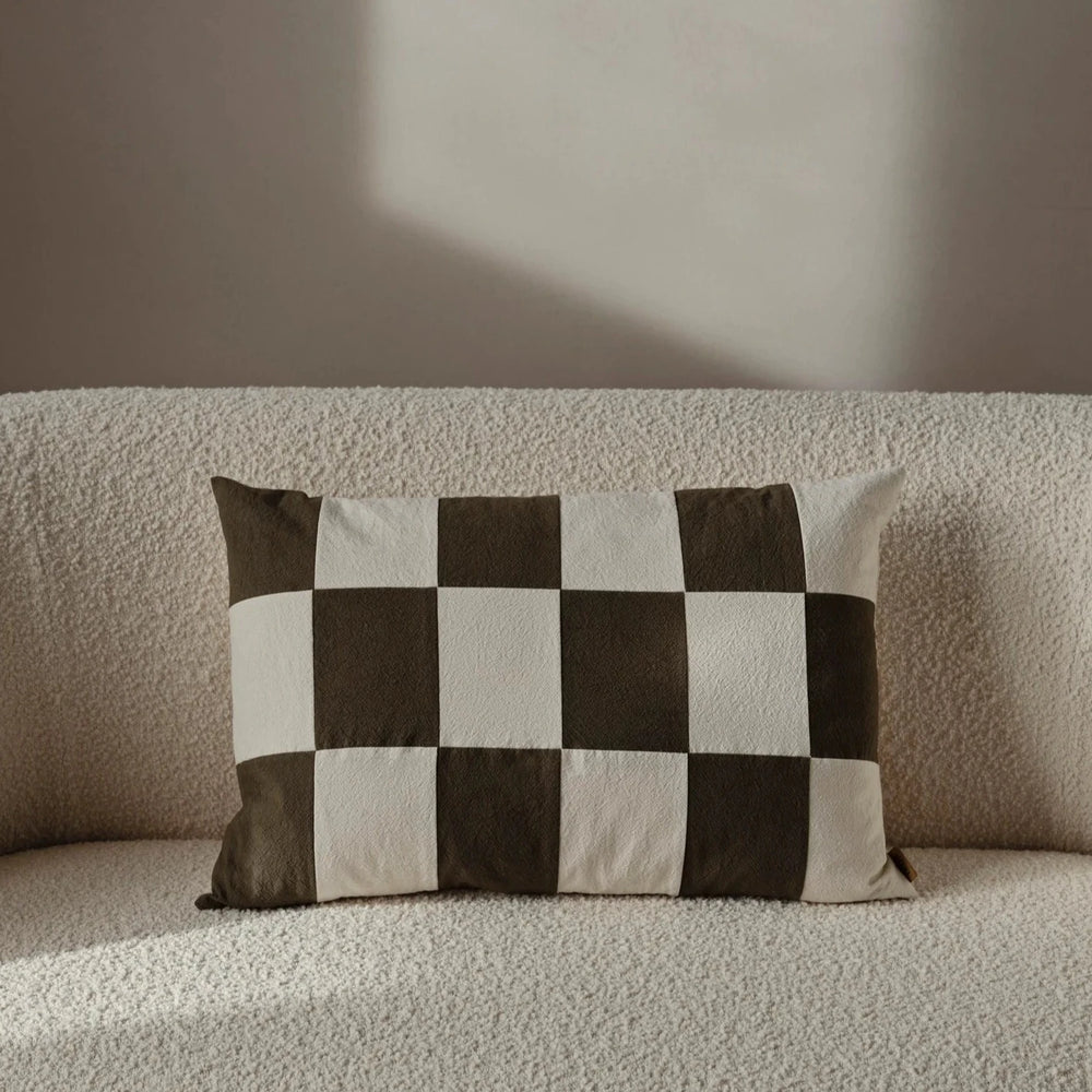 Fold Patchwork Cushion, Olive by ferm LIVING, on a cream sofa