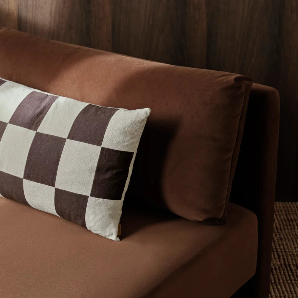 Fold Patchwork Cushion, Coffee by ferm LIVING, on a brown leather sofa