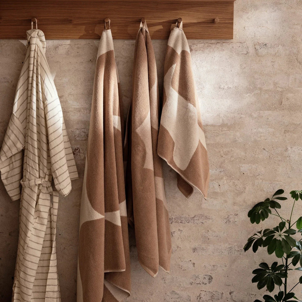 Ebb Hand Towel, Sand/Off-White by ferm LIVING, hanging on hooks
