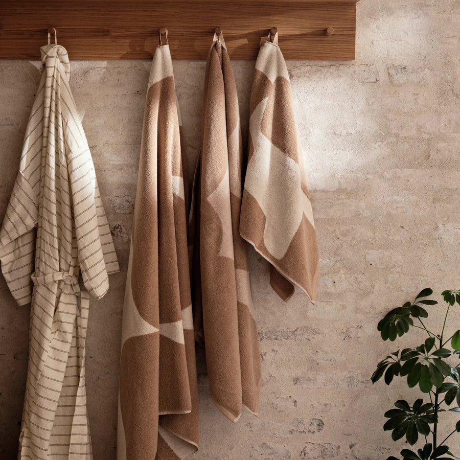 Ebb Hand Towel, Sand/Off-White by ferm LIVING, hanging on hooks