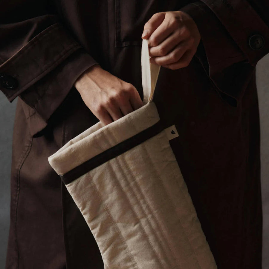Person holding a quilted cream Christmas stocking