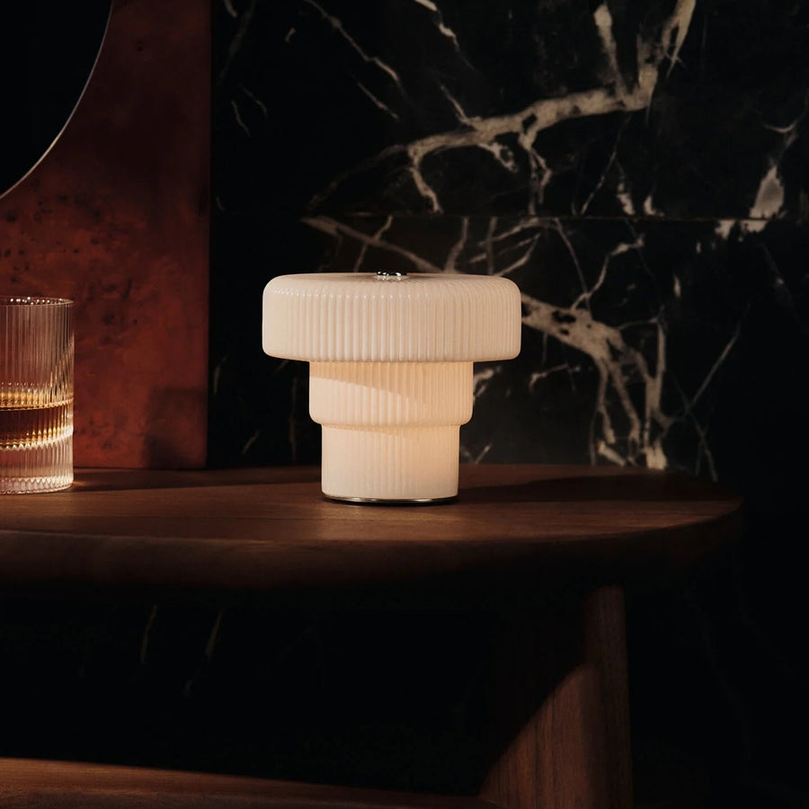 Ripple Portable Lamp, Small, White by ferm LIVING, lit on a dark marble table
