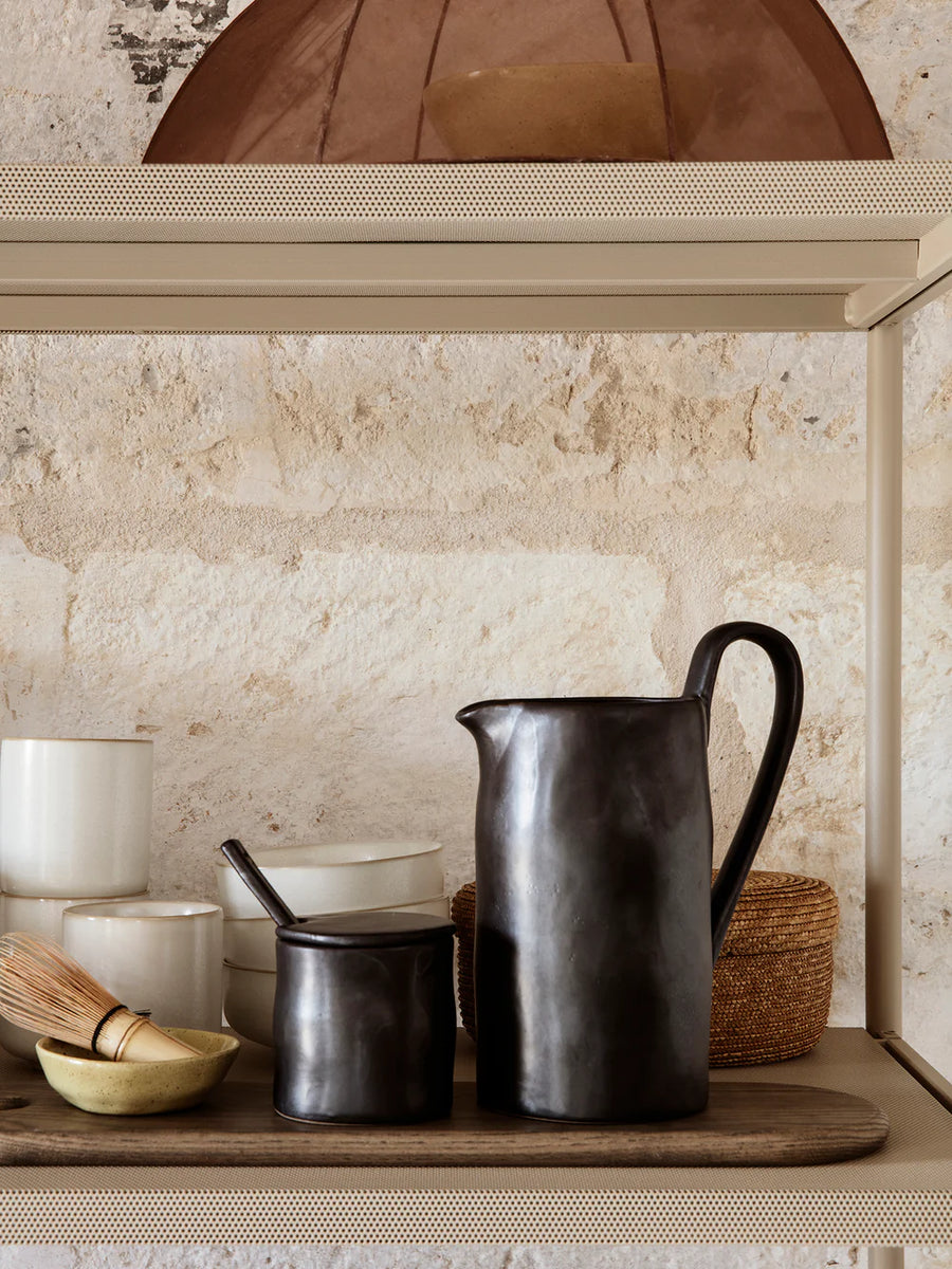 Rustic kitchen shelf with a jug and cooking pots under an arched alcove