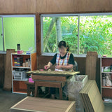 Woman sitting at a desk packaging up incense into bundles 