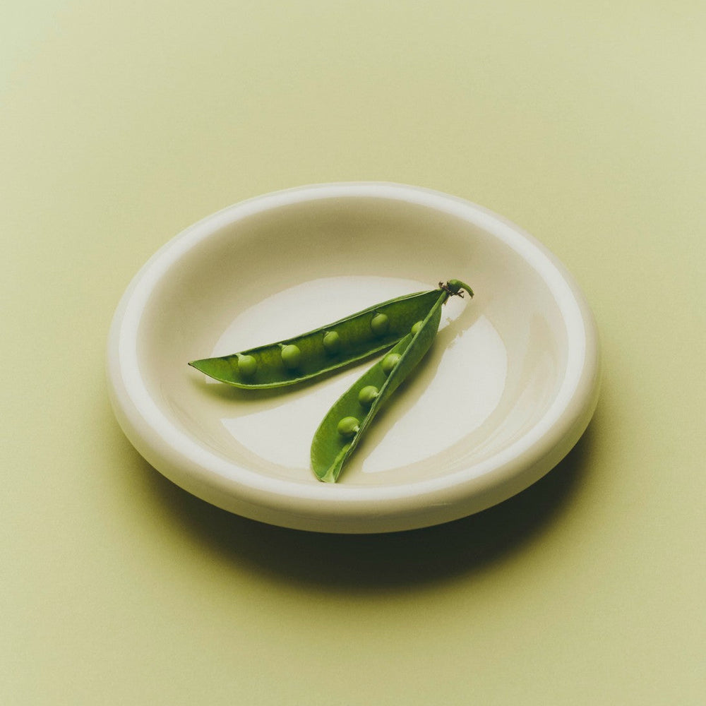 Barro Bowl, Set of Two, Off-White by HAY, holding peas on a pale green background