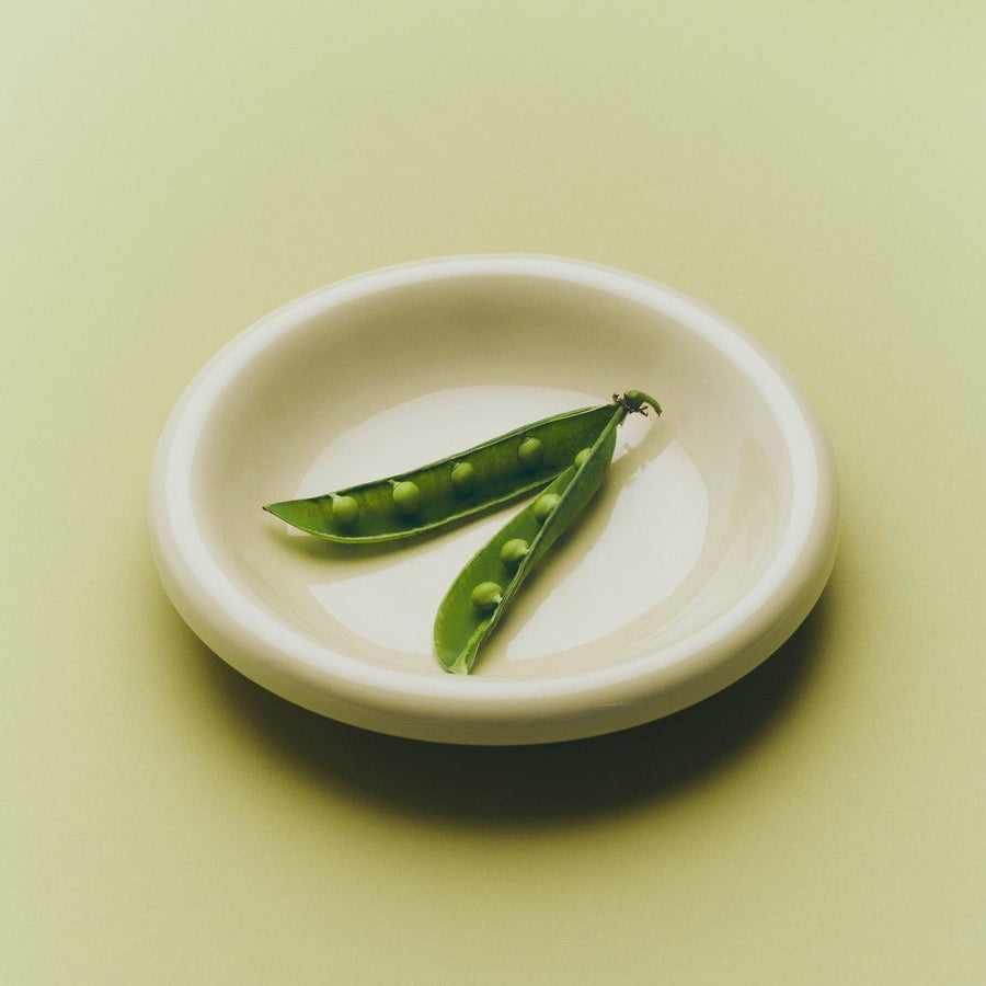 Barro Bowl, Set of Two, Off-White by HAY, holding peas on a pale green background