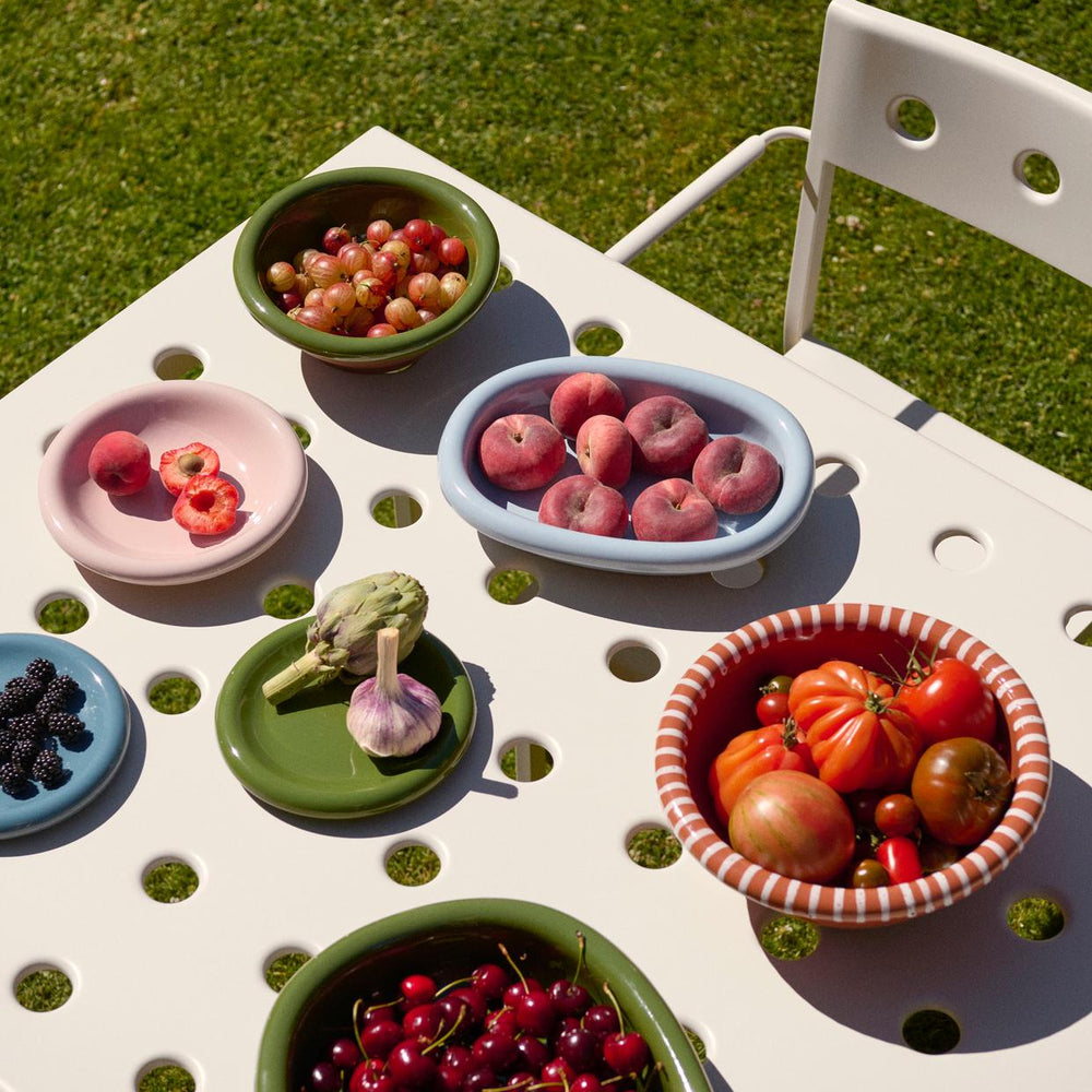 Barro Salad Bowl, Large, Natural With White Stripes by HAY, filled with fruit on a patterned tablecloth