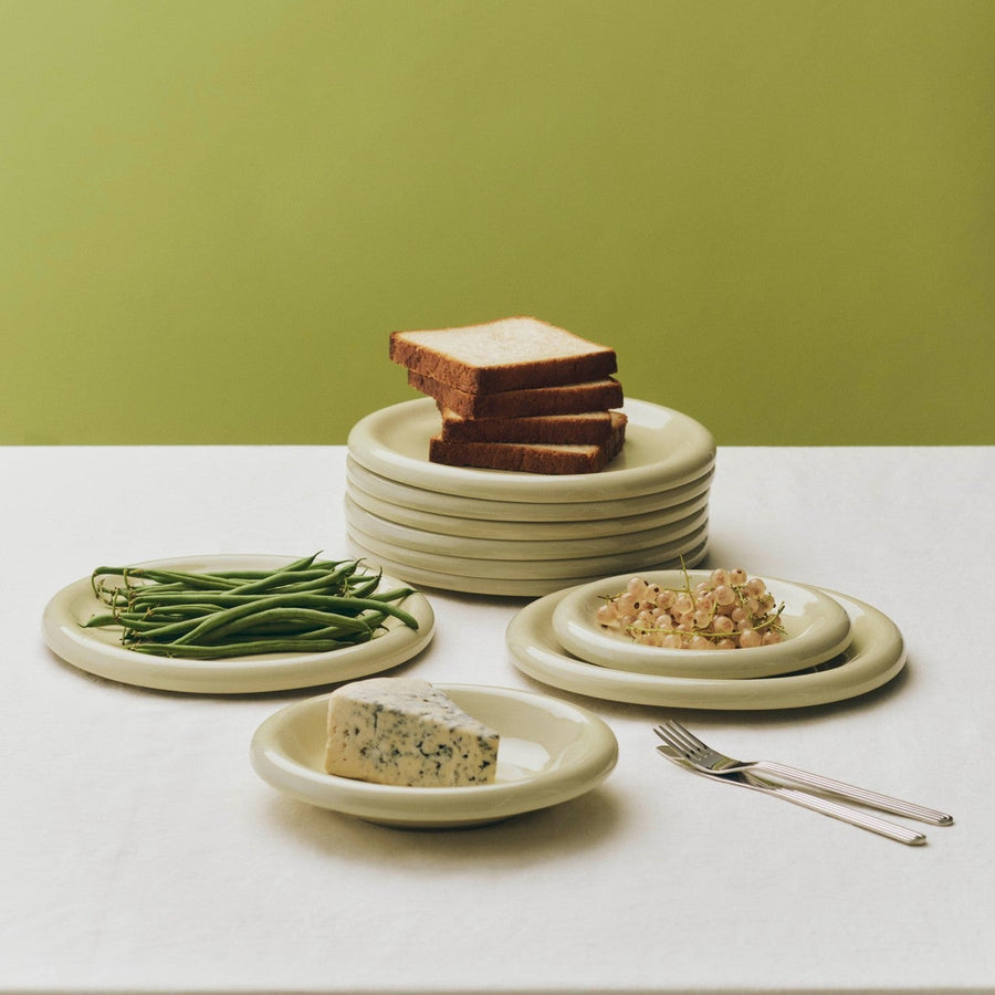 Barro Plate Set of Two, Ø18, Pistachio by HAY, stacked with bread and beans on an olive backdrop