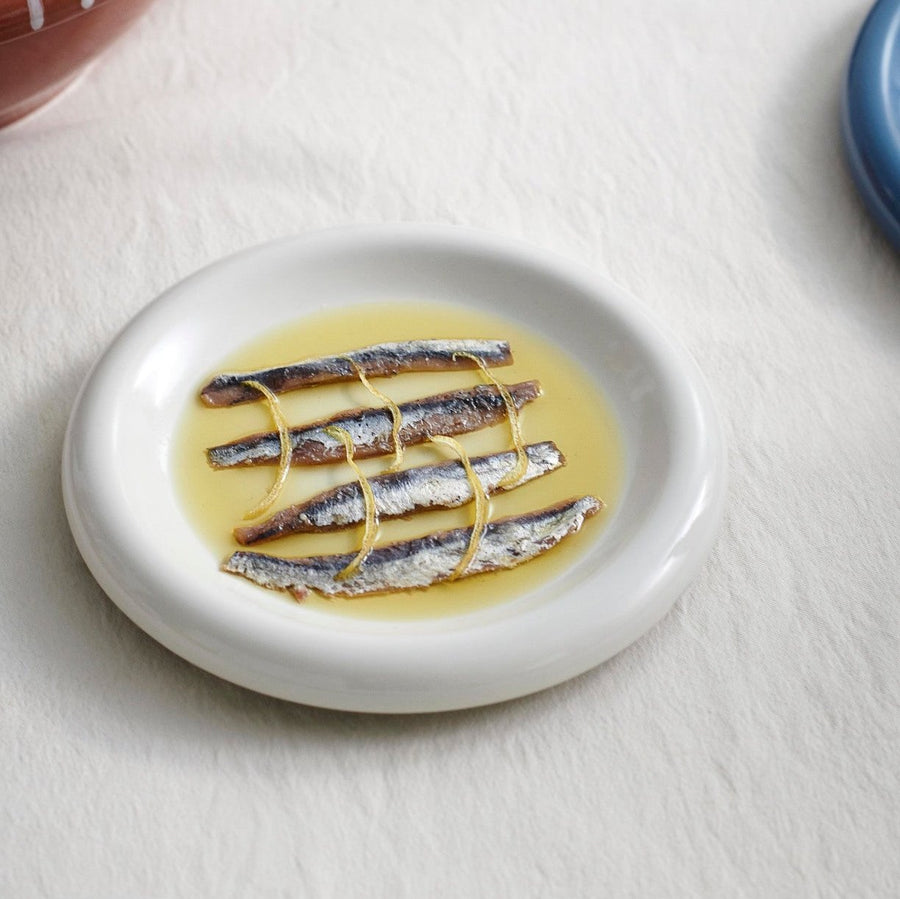 Barro Plate Set of Two, Ø18, Off-White by HAY, holding sardines on a white table