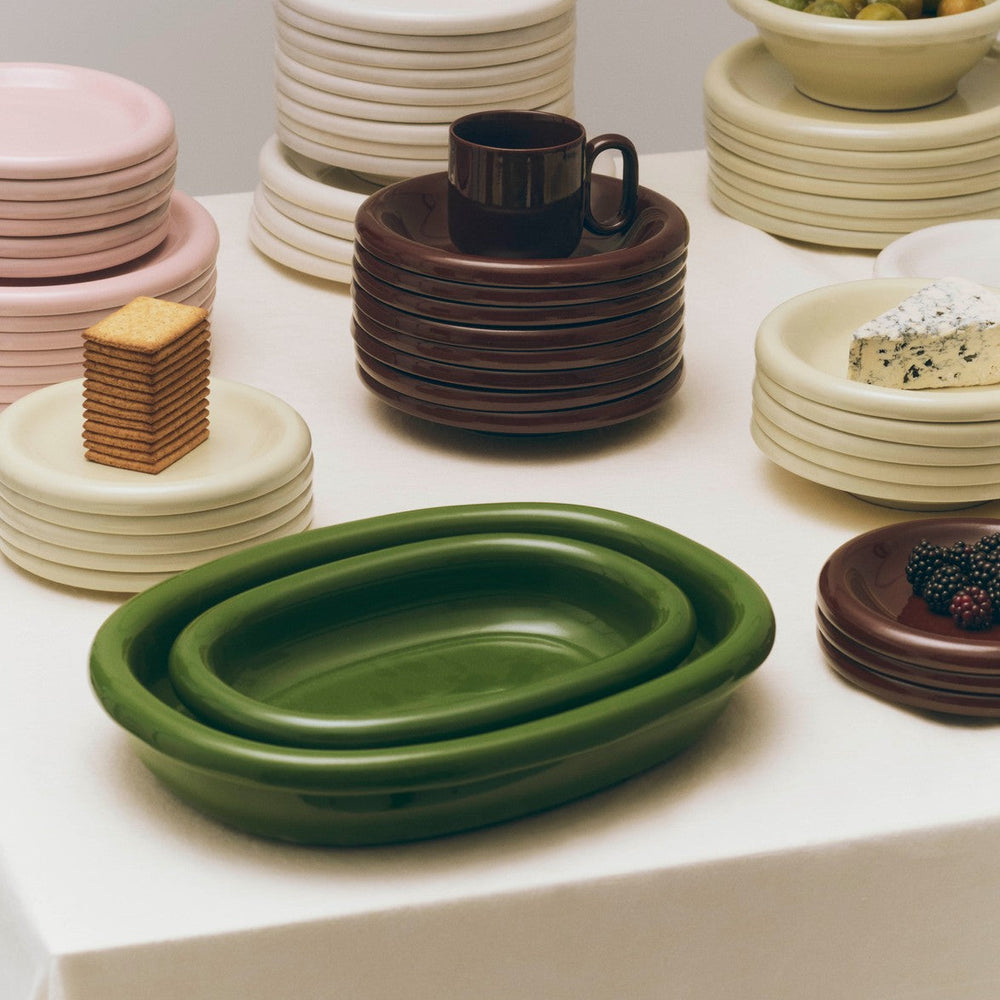 Barro Oval Dish, Small, Green by HAY, stacked with plates and bowls