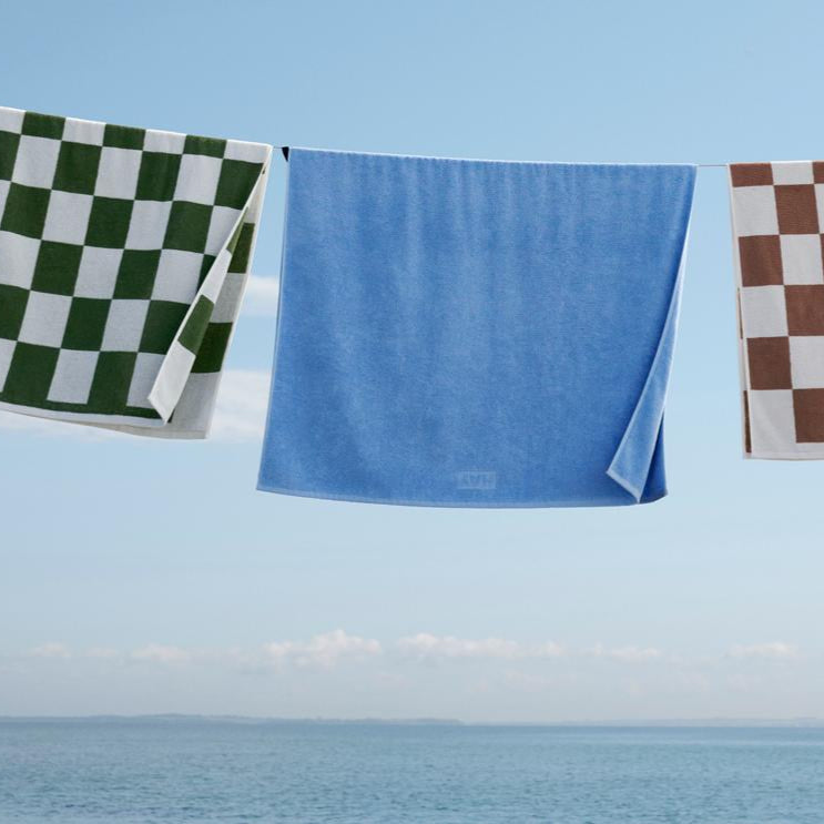 Mono Wash Cloth, Sky Blue by HAY, hanging on a line by the sea