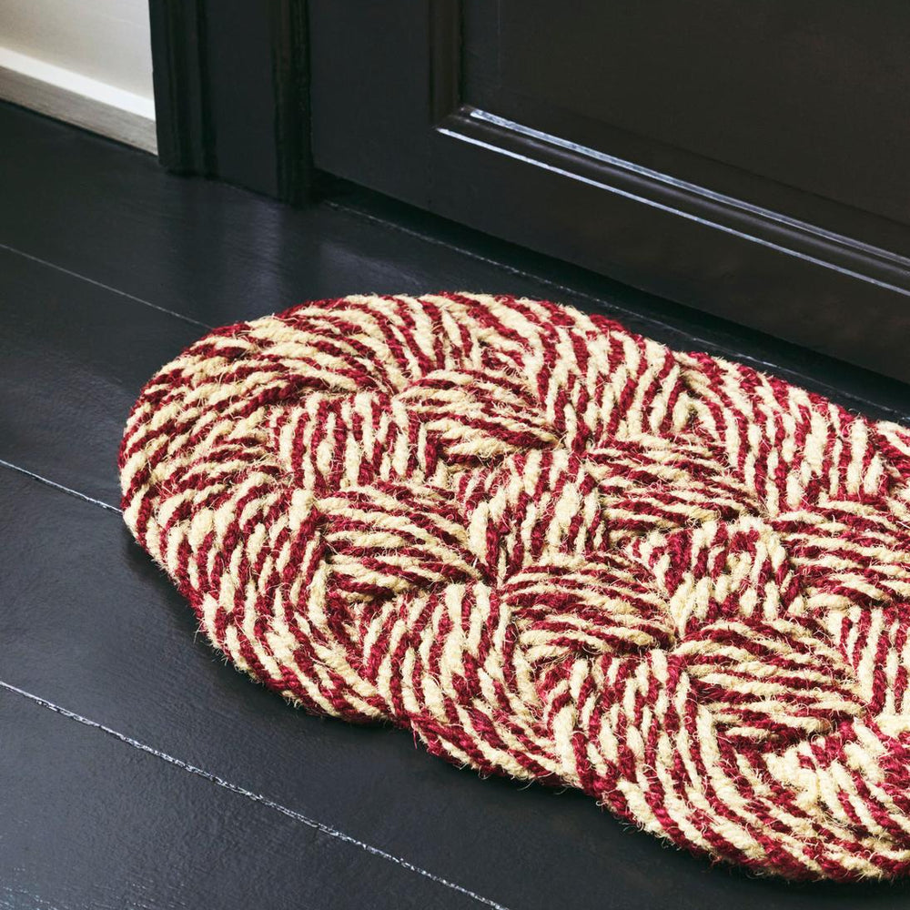 Coco Swirl Door Mat, Bordeaux & Off-White by HAY, on a wooden floor