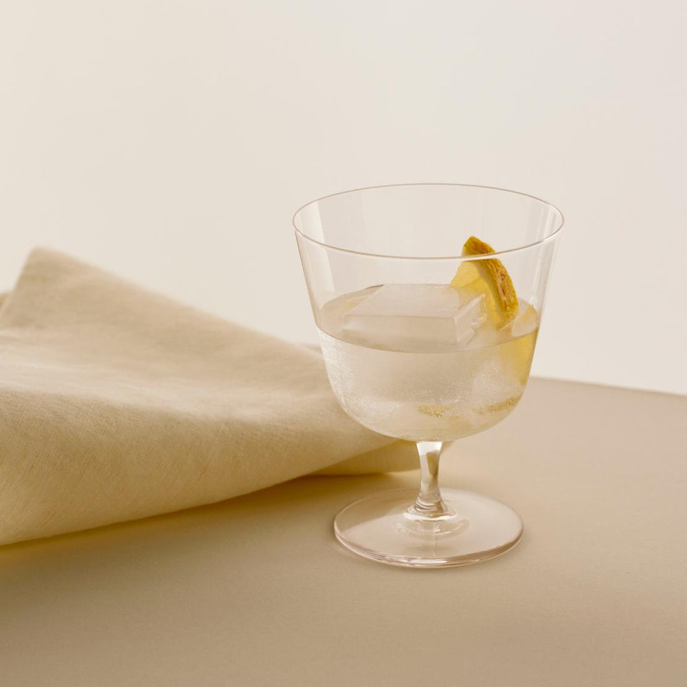 Curve Stem Glasses, Set of Two, Clear by HAY, holding a drink with a lemon twist