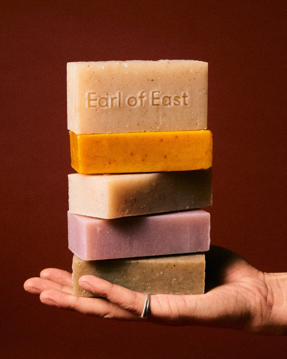 Strand Cleansing Bar Soap, 160g by Earl of East, stack of soaps held in hand