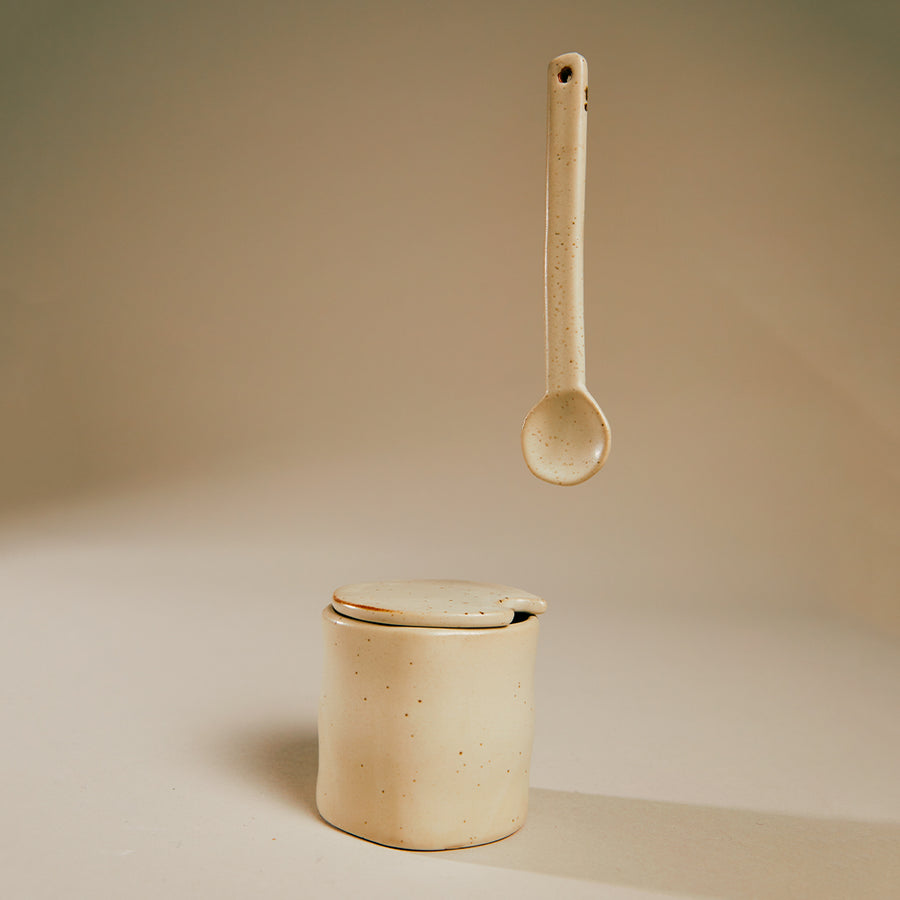 Flow Jam Jar, Off White by ferm LIVING, with a wooden spoon on a beige backdrop