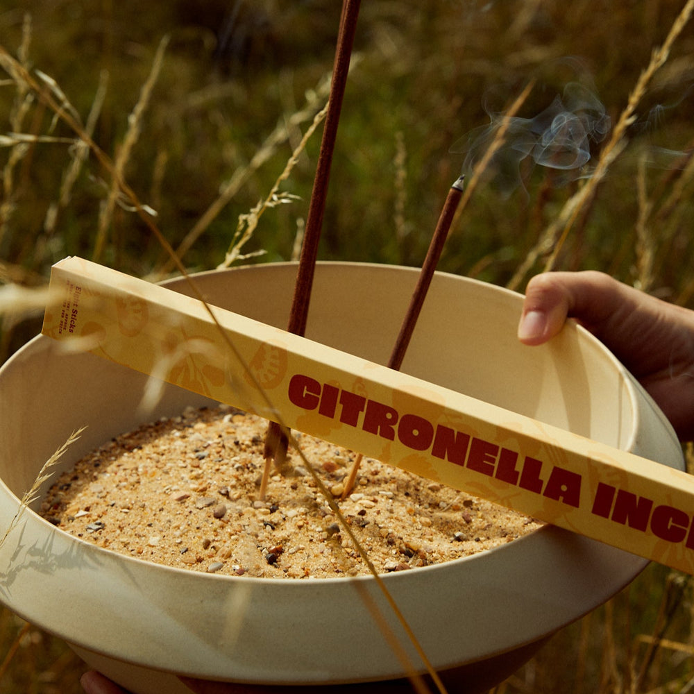 Earl of East Citronella incense in a bowl of sand outdoors