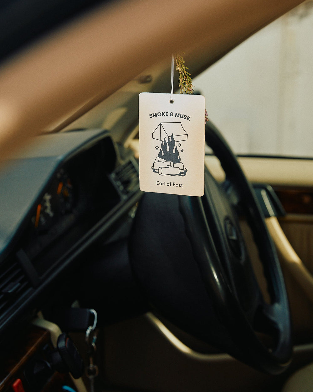Smoke & Musk Air Freshener by Earl of East, hanging from a car mirror