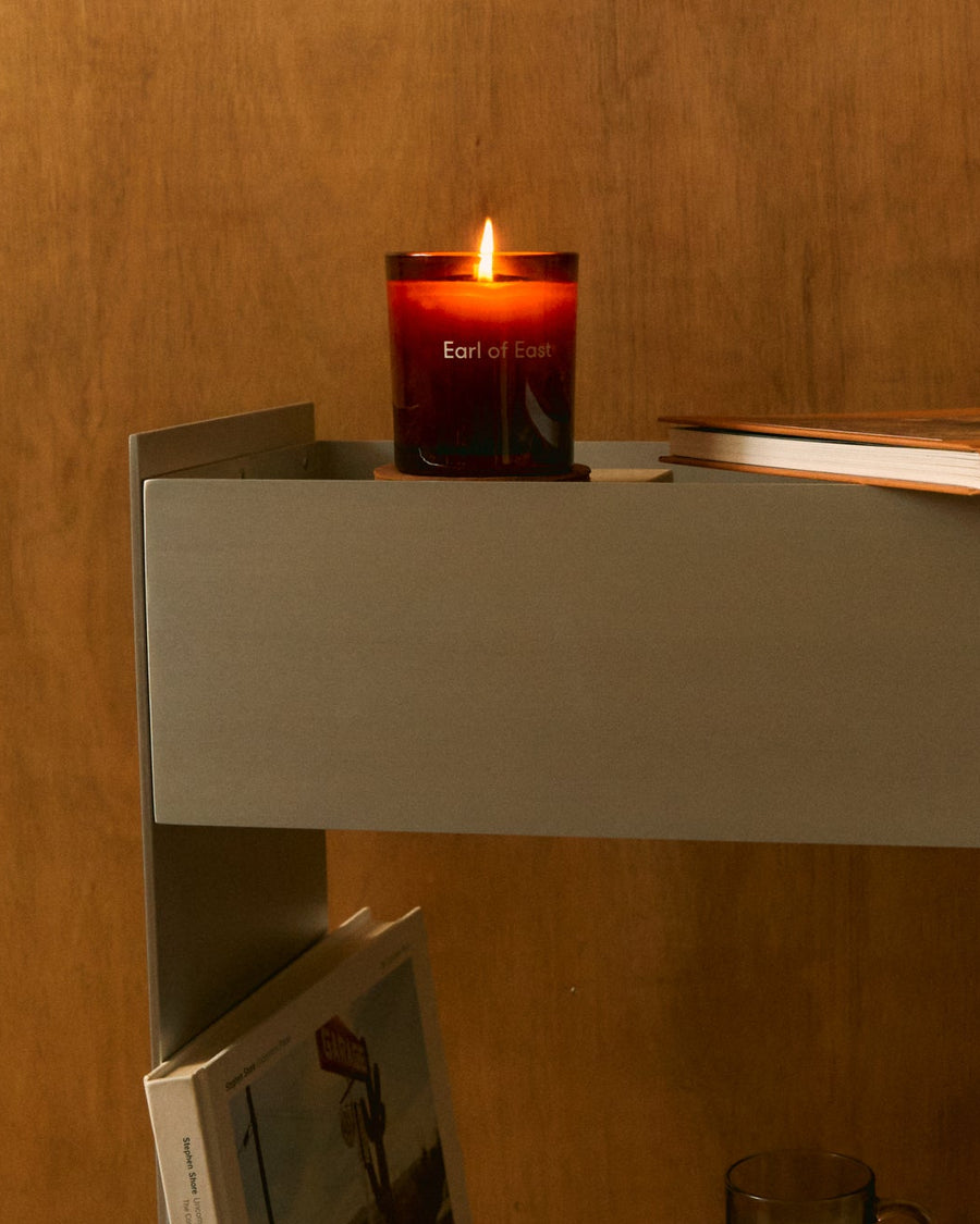 Strand Scented Candle, 260ml by Earl of East, lit on a shelf in warm light