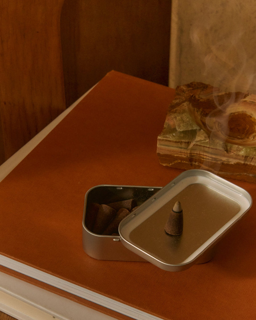 Strand Incense Cones by Earl of East, tin open on an orange surface