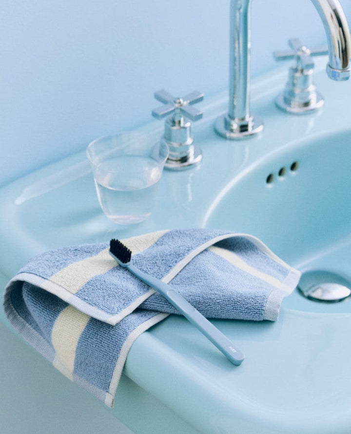 Stripe Wash Cloth in Dusty Blue by HAY, on a bathroom basin