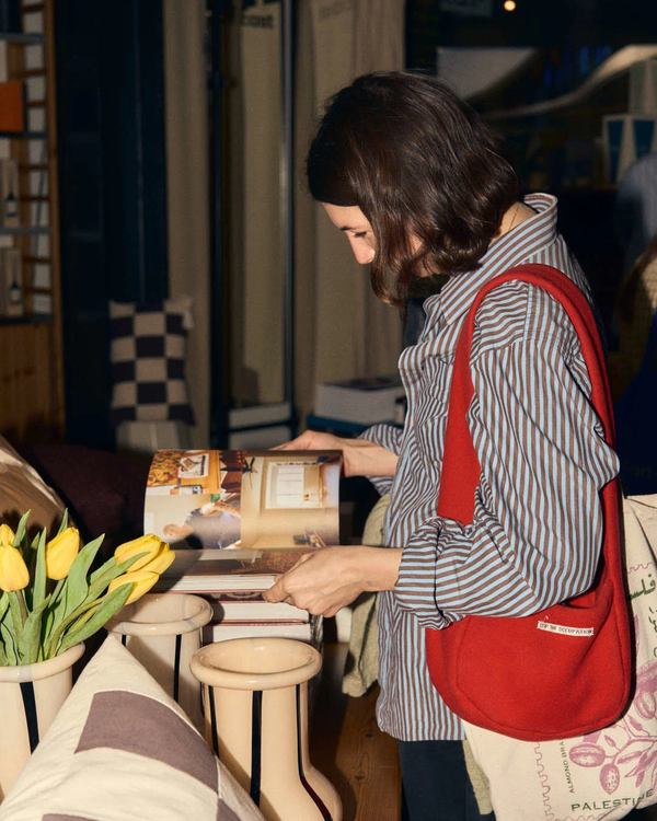 Shopper with a red bag browsing a gift table in a store