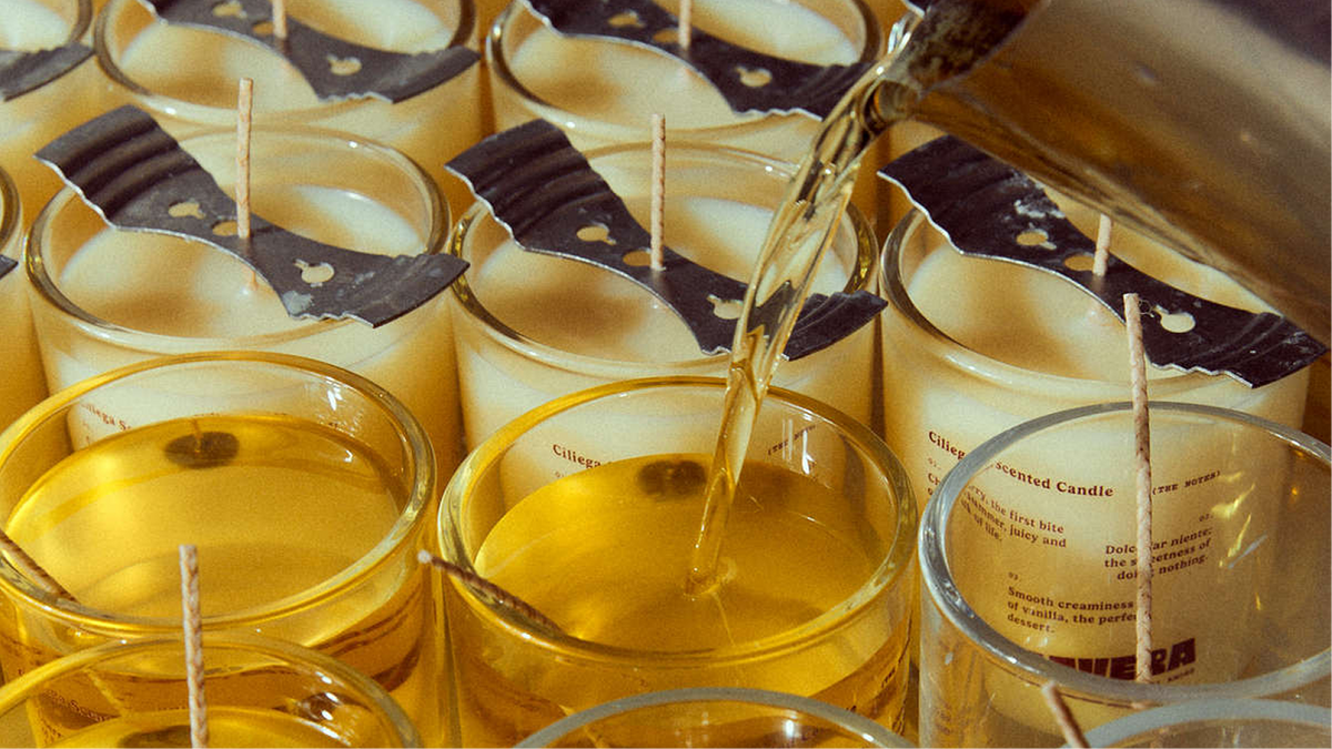 Freshly poured candles in glasses with wicks held upright