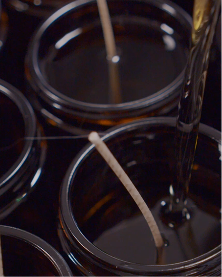 Close-up of wicks being centred in candle glasses