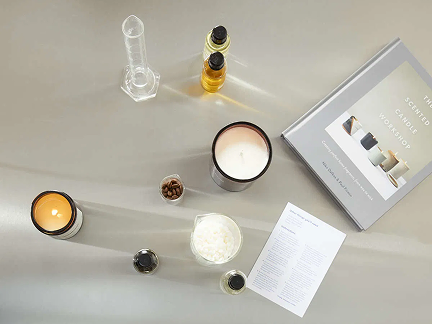 Candle making materials and fragrance bottles laid out on a white table