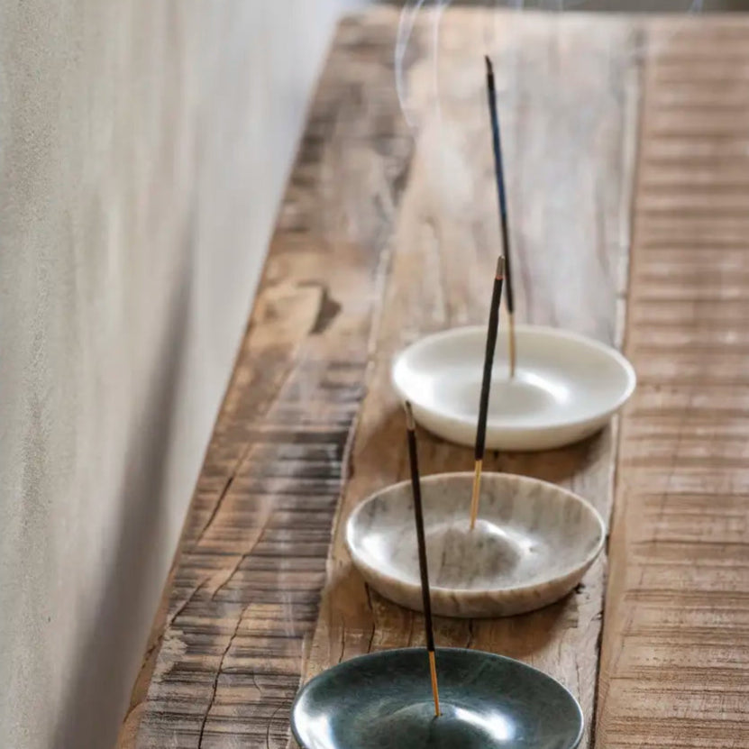 Round Marble Incense Holder, White by Madam Stoltz, holding incense on a wooden shelf