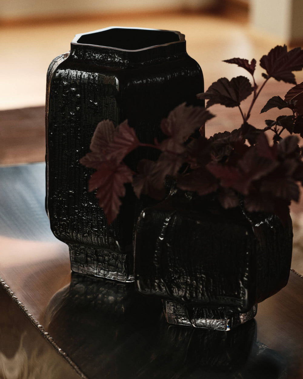 Mokuri Vase, Large, Black by ferm LIVING, holding dark foliage