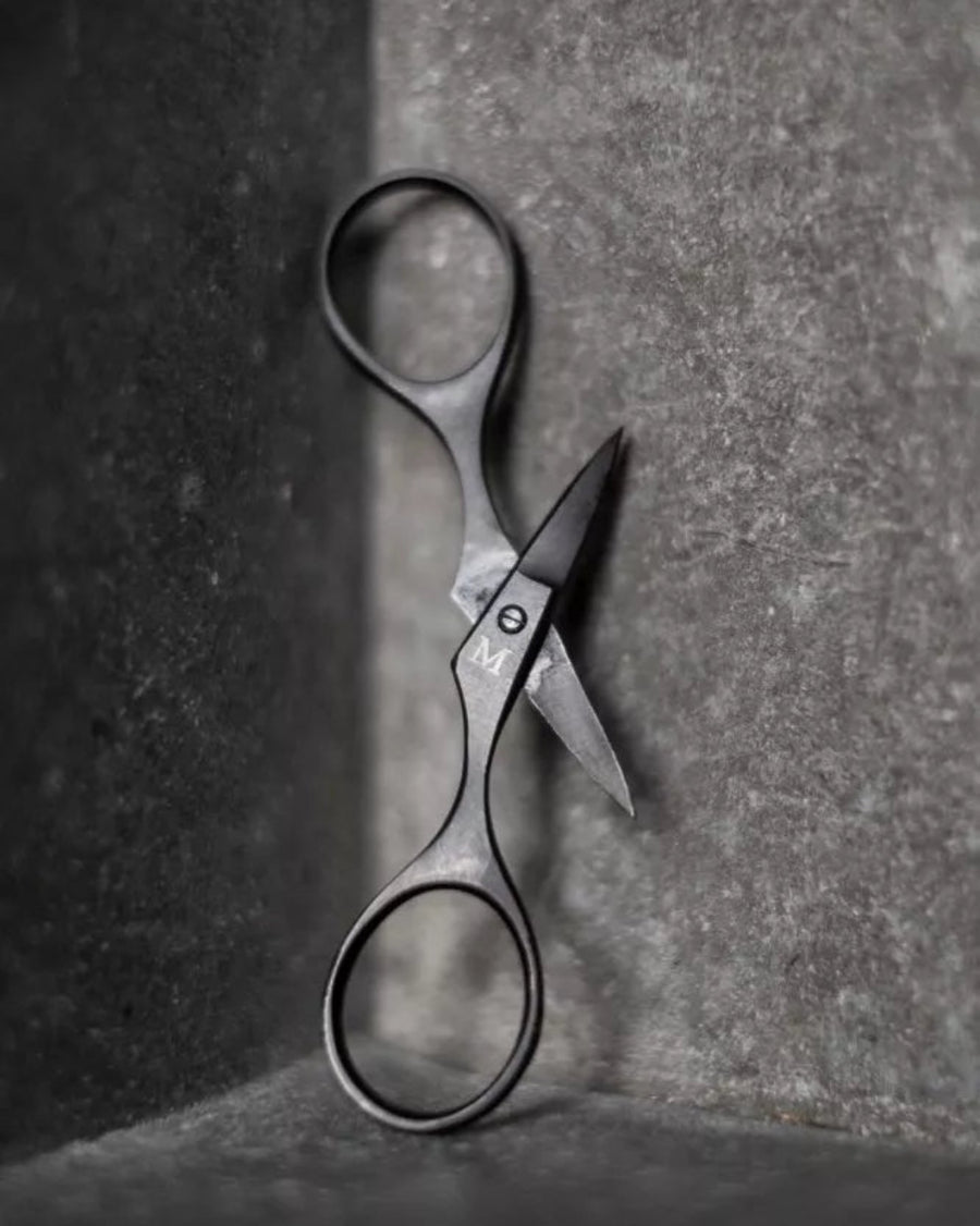 Baby Bow Scissors by Merchant and Mills, hanging on a grey background