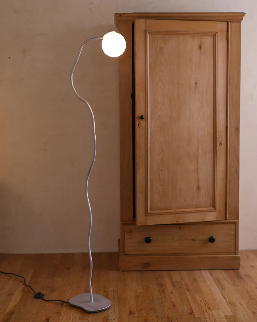 Pea Head Lamp, Aluminium by Six Dots Design, in a room with a wooden wardrobe
