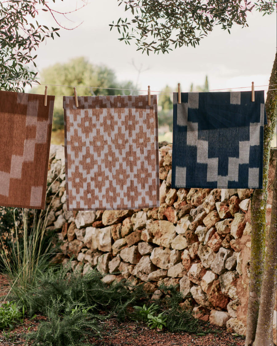 Ikat Tea Towel, Ink Blue/Parchment by ferm LIVING, hanging outdoors on a line