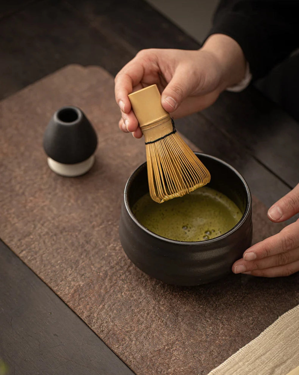 Ceramic Classic Matcha Set, Black by Gohobi, whisking matcha in a dark bowl