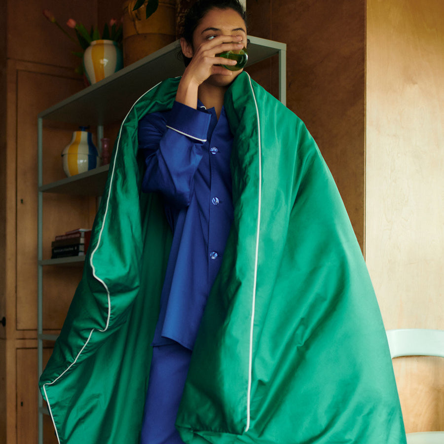Outline Pyjama, Long Sleeve Shirt, Vivid Blue by HAY, worn by a man draped in a green duvet