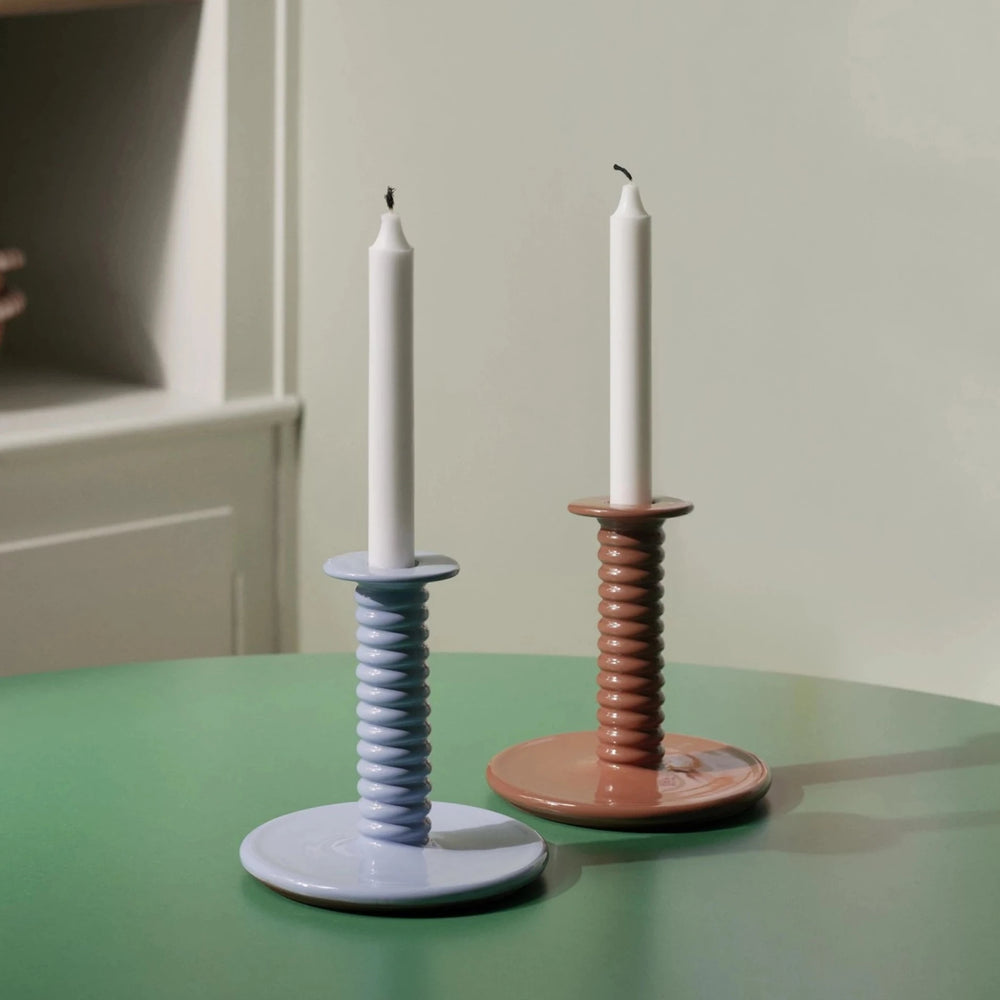 Barro Candle Holder, Light Blue by HAY, holding white candles on a green table