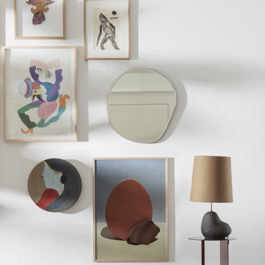 Pond Mirror, Small, Brass by ferm LIVING, among artworks on a wall