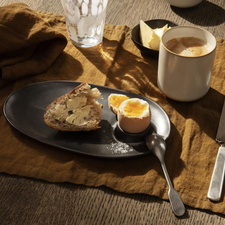Flow Breakfast Plate, Black by ferm LIVING, holding a boiled egg breakfast