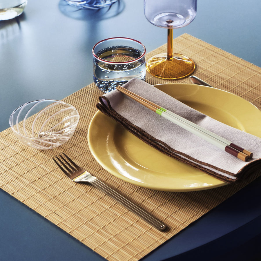 Bamboo Place Mat Set of 2, Natural by HAY, on a set table with plates and glassware