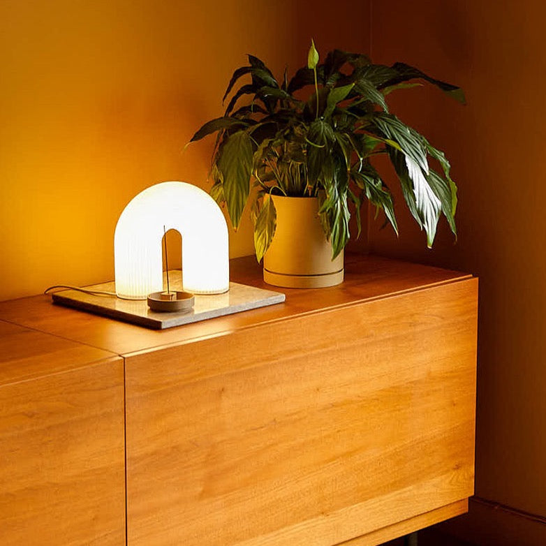 Vuelta Table Lamp by ferm LIVING, lit on a wooden sideboard