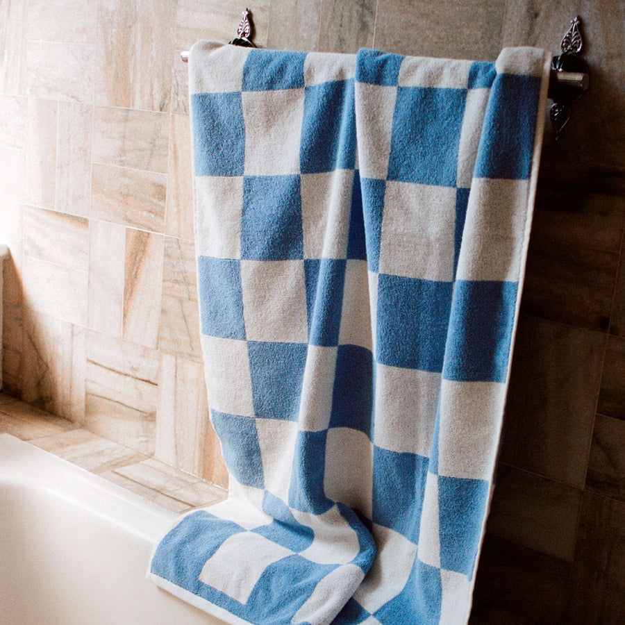Cotton Bath Towel in Sky Blue by HAY, hanging in a bathroom